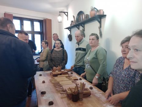 Zdjęcie przedstawia grupę ludzi stojących wokół stołu przygotowanego do wyrobu pierników. 