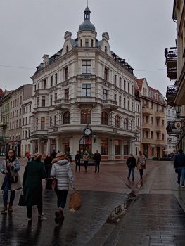 Zdjęcie przedstawia liczną grupę przechodnich turystów, znajdujących się na tle pięknie zdobionej budowli.